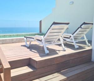 due sedie bianche sedute su una terrazza con vista sull'oceano di Loft acogedor con área de parrilla y piscina a Punta Hermosa