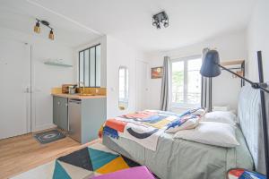 um quarto com uma cama com um candeeiro e uma cozinha em Studio Parisien - Quai Valmy em Paris