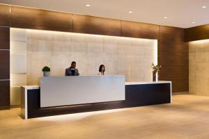 a man and woman standing at a reception desk in a lobby at AC Hotel Cincinnati at Liberty Center in West Chester