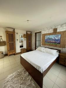 a bedroom with a bed and a painting on the wall at DUPLEX MONTECARLO in Ubatuba