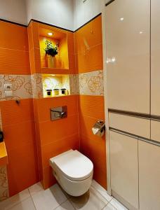 a bathroom with a toilet and orange walls at Apartament Mazurska Natura in Szczytno