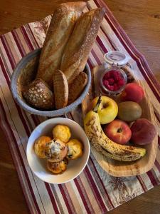 a table with a plate of bread and a bowl of fruit at CHAMBRES D'HÔTES LES CHAMBRES D'ELSA in Albiez-Montrond