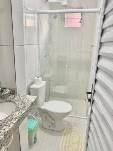 a white bathroom with a toilet and a shower at Suite 237 in Itanhaém