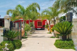einen Innenhof mit Palmen und einem roten Gebäude in der Unterkunft B&B Lizia in Porto Cesareo