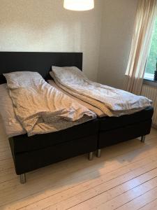 an unmade bed with a black frame in a bedroom at Lägenhet på Strömsholm in Jönköping
