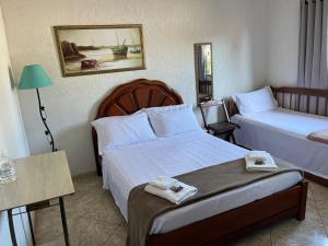 a hotel room with two beds and a table at Hospedagem Clã dos Couto - Pousada in Saquarema