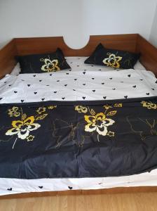 a bed with a black and yellow comforter and pillows at Casa Drumețului in Făgăraş