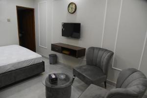 a room with a bed and a chair and a tv at Hotel white season Gulberg in Lahore