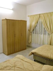 a bedroom with two beds and a cabinet and a window at شقه النزهه مكونه من غرفتين وصاله ودورتين مياه وغرفه طعام in Al Madinah