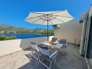 um pátio com uma mesa e um guarda-chuva em Apartman Portorus em Lastovo