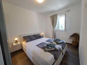 a bedroom with a white bed with two pillows on it at Apartman Portorus in Lastovo