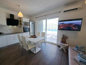 a kitchen and dining room with a white table and chairs at Apartman Portorus in Lastovo