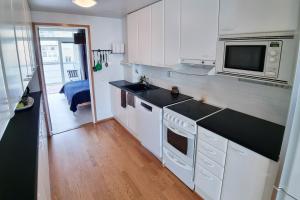 cocina con armarios blancos y microondas en Idas AirBnB en Helsinki