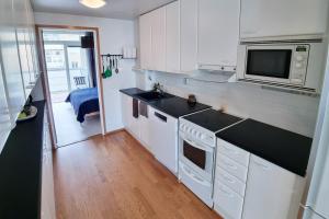 a kitchen with white cabinets and a microwave at Idas AirBnB in Helsinki
