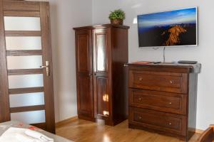 a bedroom with a dresser and a tv on a wall at Apartamenty Parzenica in Zakopane