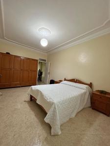 a bedroom with a bed with a white comforter at Sfiha/Hoceima huis in Al Hoceïma