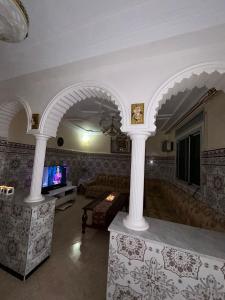 een woonkamer met zuilen, een bank en een tv bij Sfiha/Hoceima huis in Al Hoceïma