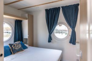 a bedroom with two windows with blue curtains at Marina del Gargano Houseboat in Manfredonia