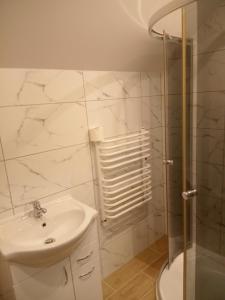 a white bathroom with a sink and a shower at Dom Wypoczynkowy Nad Wisłą in Puławy