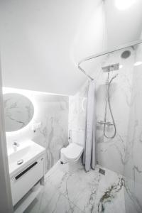 a white bathroom with a toilet and a sink at Apartamentai Ieva Kunigiškėse in Palanga