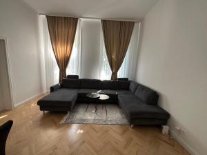 Schöne 2 Zimmer Apartment im Wiener Altbaustil nahe Donaukanal في فيينا: غرفة معيشة مع أريكة سوداء وطاولة