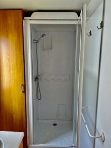 W łazience znajduje się prysznic ze szklanymi drzwiami. w obiekcie Bumgalow 5X w mieście Pataias