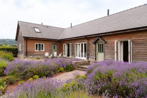 a wooden house with purple flowers in front of it at Stunning lodge in idyllic rural Herefordshire in Dorstone