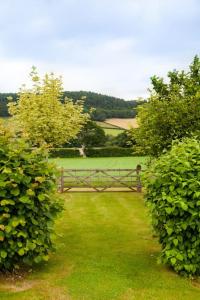 a wooden gate in a field with green bushes at Stunning lodge in idyllic rural Herefordshire in Dorstone