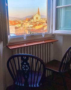 - une fenêtre avec 2 chaises, une table et 2 verres à vin dans l'établissement Casa Pavó Appartamento accanto al Bargello, à Florence