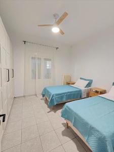 a bedroom with two beds and a ceiling fan at Asmini Beach Apartments in Asmínion