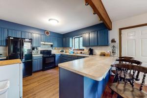 a large kitchen with blue cabinets and a counter top at The Burrow in Jim Thorpe