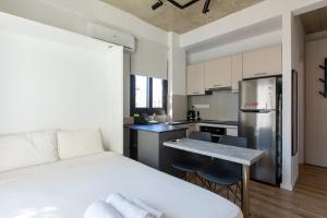 a bedroom with a white bed and a kitchen at YAMAS Urban LIving Spiridonos in Limassol