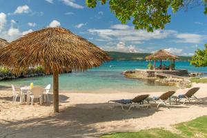 una spiaggia con sedie, ombrellone di paglia e acqua di Sunny Vacation Villa No 8 a Mandeville