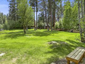 un parc avec un banc en bois dans la pelouse dans l'établissement Metolius Cabin 6, à Camp Sherman