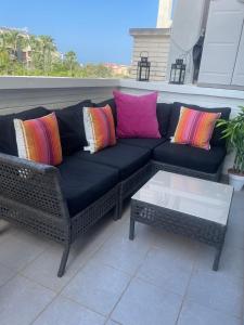 un divano nero con cuscini colorati su un patio di Fabulous Apartment with large pool near beach a Denia