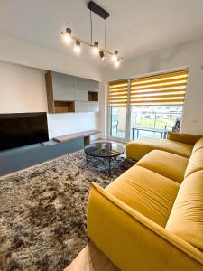 a living room with a yellow couch and a table at BG LUXIMMO APARTMENTS in Cluj-Napoca