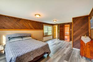 a bedroom with a bed and a wooden wall at Cozy Livingston Manor Home with Wood-Burning Stove! in Livingston Manor