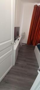 a room with a desk with a television and a door at katyra house in Aubervilliers