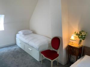 ein kleines Schlafzimmer mit einem Bett und einem roten Stuhl in der Unterkunft Maison de Village Vexin site classé 1h Paris et Normandie grand jardin in Reilly