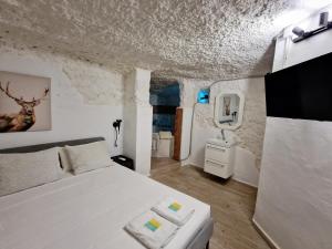 1 Schlafzimmer mit einem weißen Bett und einem TV in der Unterkunft PRECIOSA CASA-CUEVA CON JACUZZI in Paterna