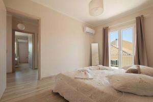 a white bedroom with a large bed and a window at Βιλα Fiore in Avliótai