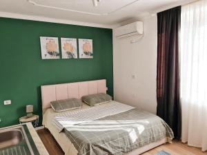 ein Schlafzimmer mit einem Bett und einer grünen Wand in der Unterkunft Casa 21 - the cutest in Tirana! in Tirana