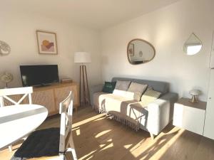 a living room with a couch and a tv at Cabourg cosy, appartement refait à neuf, 5 min à pied de la mer in Cabourg