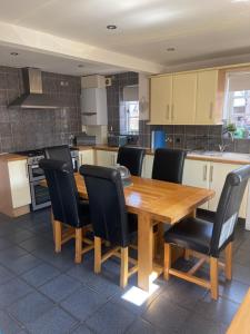 een keuken met een houten tafel en zwarte stoelen bij Forgemasters House in Telford