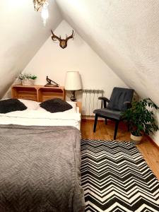 a attic bedroom with two beds and a chair at Domek dla dwojga in Tylicz