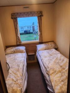 Woods caravan في إنغولدميلز: سريرين في غرفة صغيرة مع نافذة