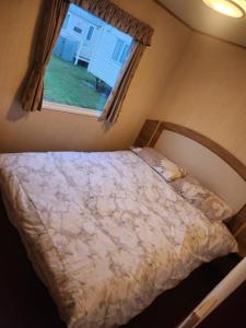 a bedroom with a large bed with a window at Woods caravan in Ingoldmells