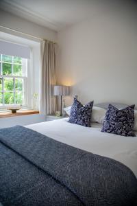 um quarto com uma grande cama branca com almofadas azuis em Balmungo Cottage B&B em St Andrews