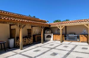 an outdoor patio with a roof and a grill at La grange des Bardins in Blanzaguet-Saint-Cybard-le-Peyrat