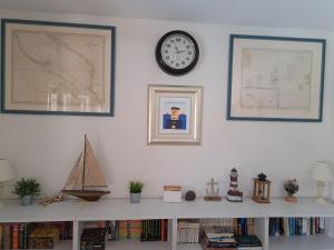 a shelf with a clock on a white wall with books at Holiday home Voga in Maslinica